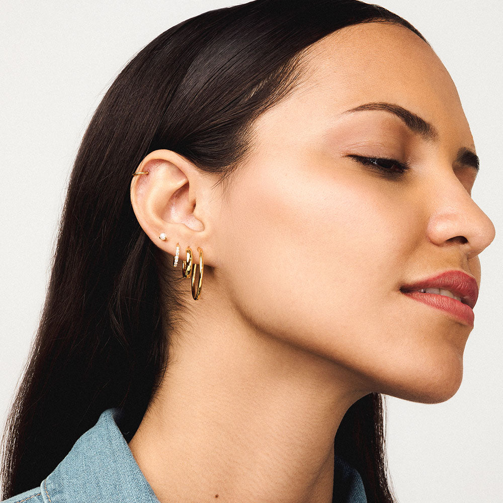 Pearl Nap Earring in gold on model paired with Classic Cartilage, Bold Hoop, Eternity Hoop and Classic 1