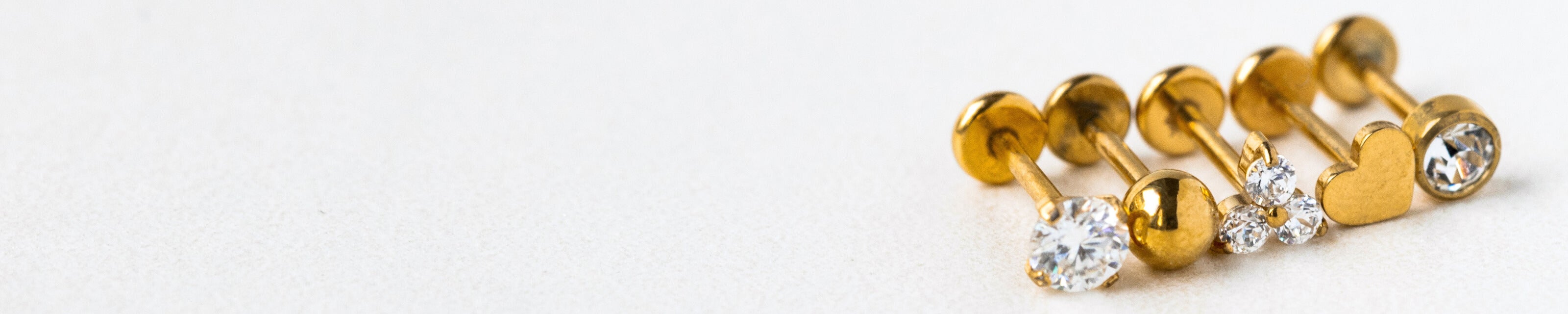 Gold earrings with clear gemstones on a light gray background