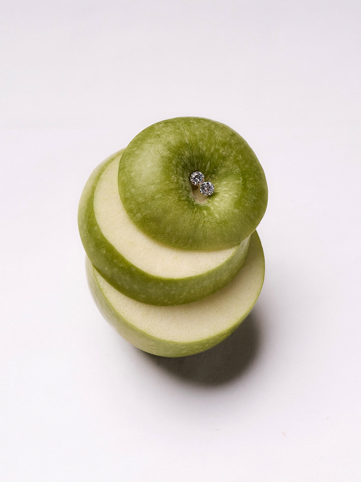 Crystal solitaire earrings on sliced green apple