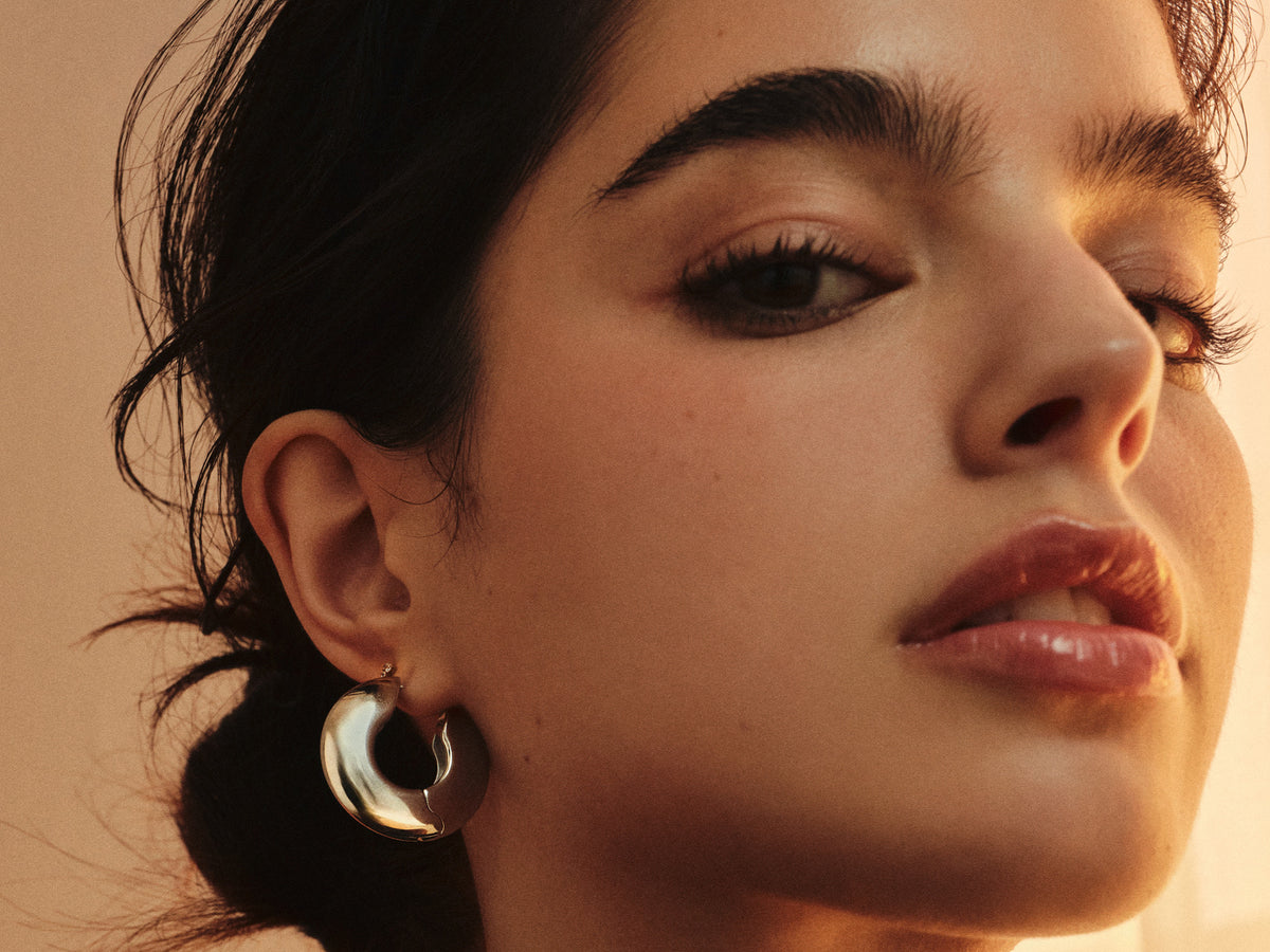 Close-up of a woman wearing a sculptural silver-tone statement hoop