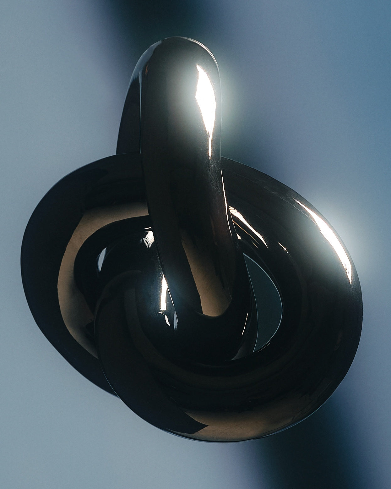 Glossy metal rings intertwined against a blue-gray background